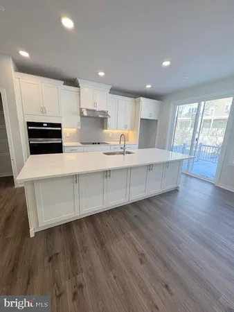 a large kitchen with stainless steel appliances wooden floors and wooden cabinets