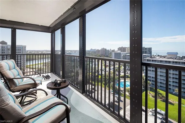 a balcony with furniture and floor to ceiling windows