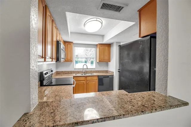 a kitchen with stainless steel appliances granite countertop a refrigerator and a sink