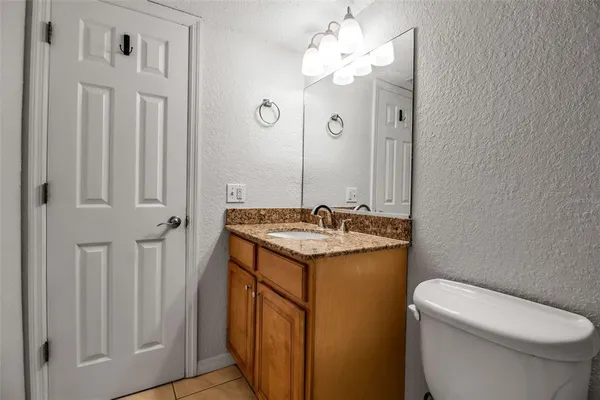 a bathroom with a granite countertop sink a toilet and a mirror