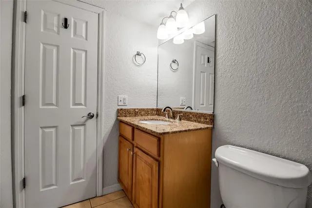 a bathroom with a granite countertop sink a toilet and a mirror