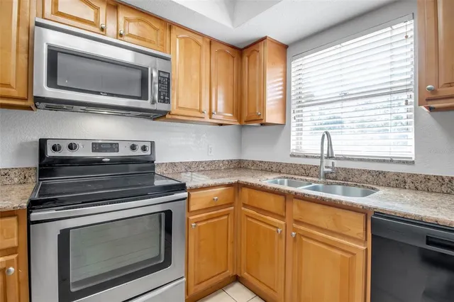 a kitchen with granite countertop cabinets stainless steel appliances a sink and window