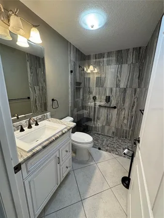 a bathroom with a granite countertop sink toilet a mirror and shower