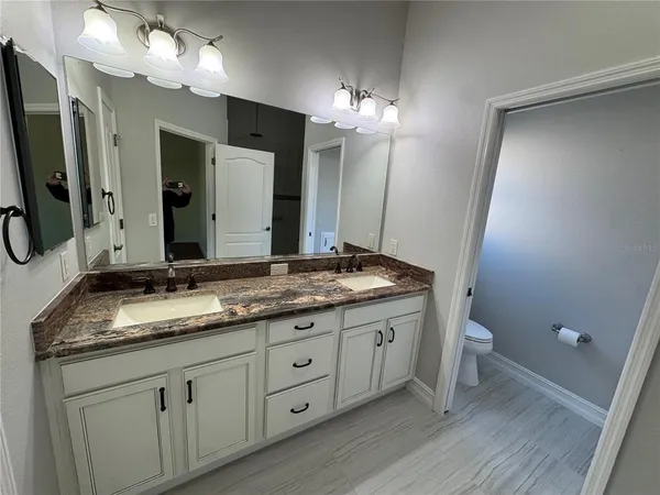 a bathroom with a granite countertop sink toilet and mirror