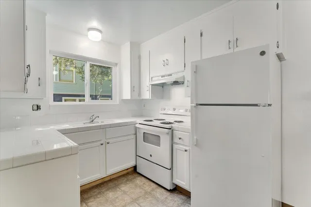 a kitchen with white cabinets and white appliances