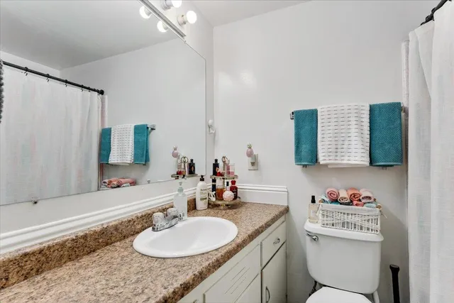 a bathroom with a granite countertop sink mirror and a toilet