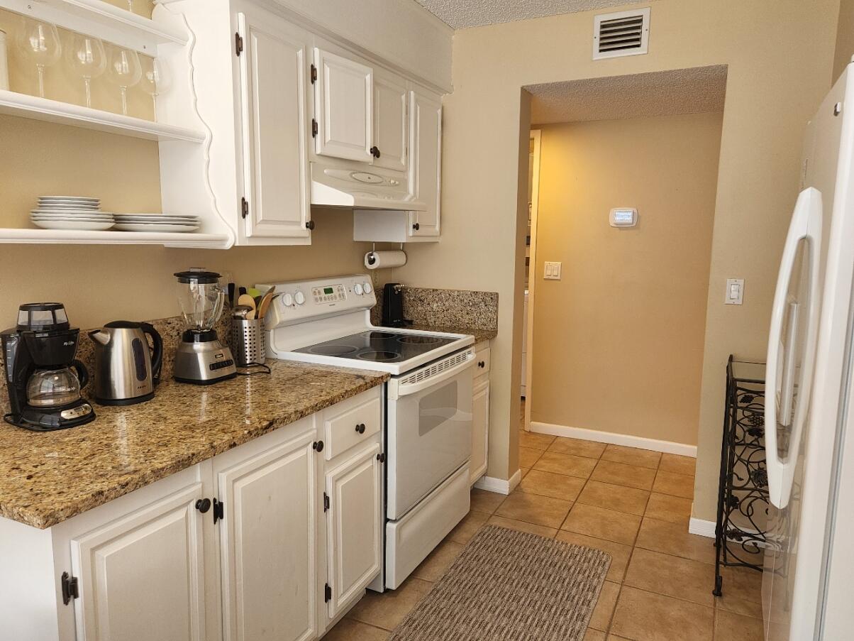 a kitchen with granite countertop a sink stainless steel appliances a refrigerator and cabinets