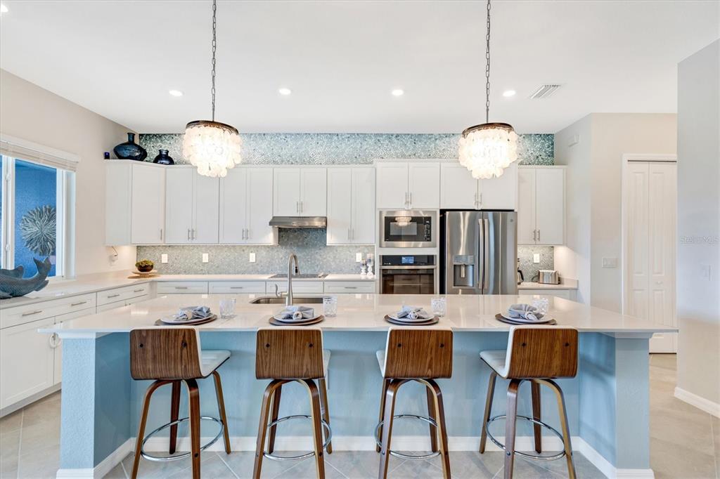 12736 Tulum Loop Venice, FL 34293 - Photo 8 of 93 a kitchen with stainless steel appliances kitchen island granite countertop a table chairs and a sink