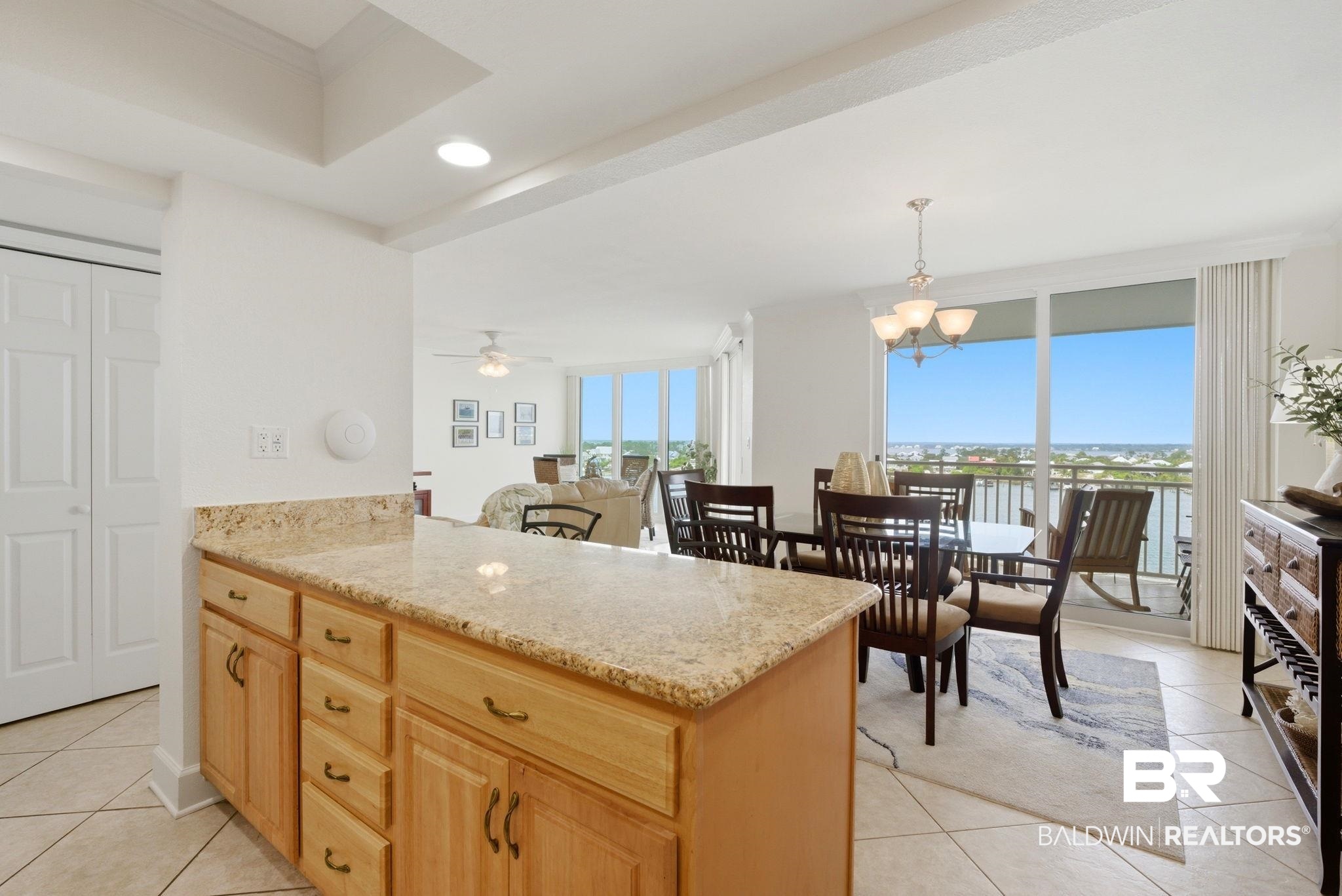 16284 Perdido Key Drive, Unit 912 Perdido Key, FL 32507 - Photo 28 of 49 Kitchen featuring light tile patterned flooring, a peninsula, hanging lights, light stone counters, and light wood finish cabinets