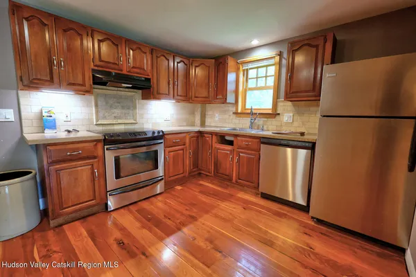 a kitchen with stainless steel appliances granite countertop white cabinets a sink a stove a refrigerator and with wooden cabinets