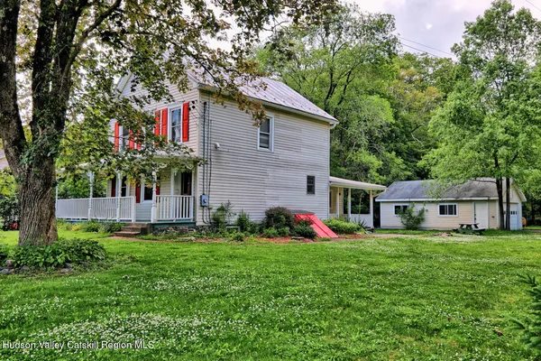 a front view of a house with a garden and trees
