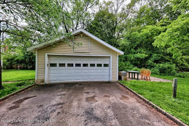 a view of a house with a yard plants and large tree