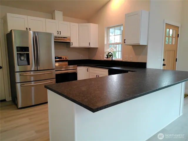a kitchen with stainless steel appliances granite countertop a sink a stove and a refrigerator