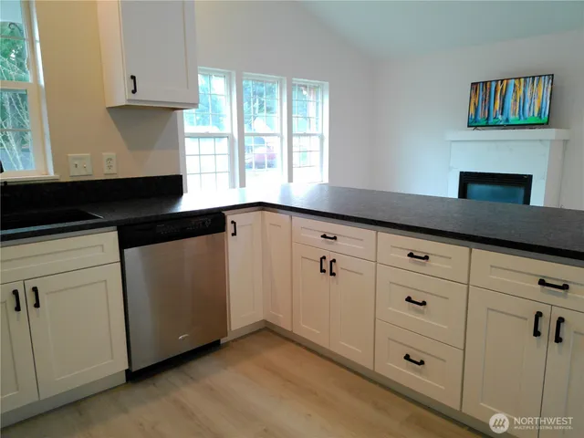a kitchen with granite countertop white cabinets and black stainless steel appliances