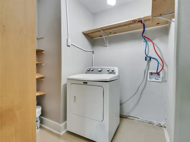 an empty room with a kitchen and a chandelier fan