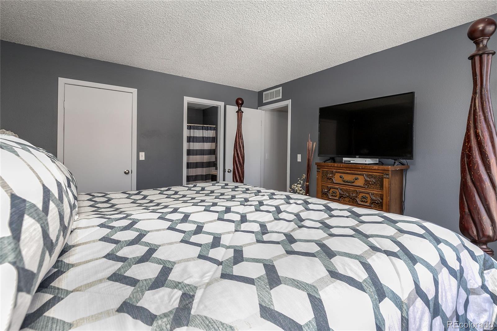 8741 Dawson Street, Unit 304 Denver, CO 80229 - Photo 18 of 27 a bedroom with a bed and a flat screen tv