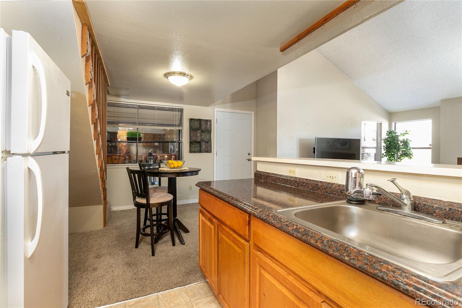 8741 Dawson Street, Unit 304 Denver, CO 80229 - Photo 9 of 27 a kitchen with granite countertop a sink and a refrigerator