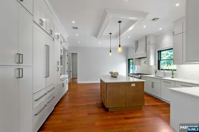 a large white kitchen with lots of counter space wooden floor and appliances