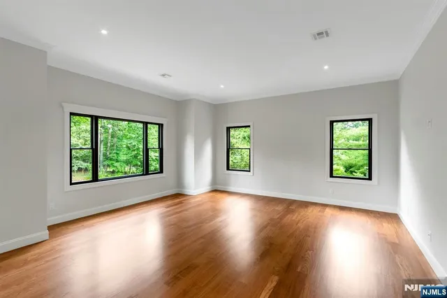 a view of an empty room with wooden floor and windows