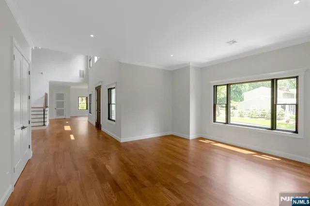 a view of an empty room with window and wooden floor