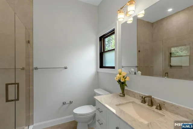 a bathroom with a granite countertop sink a toilet and a mirror