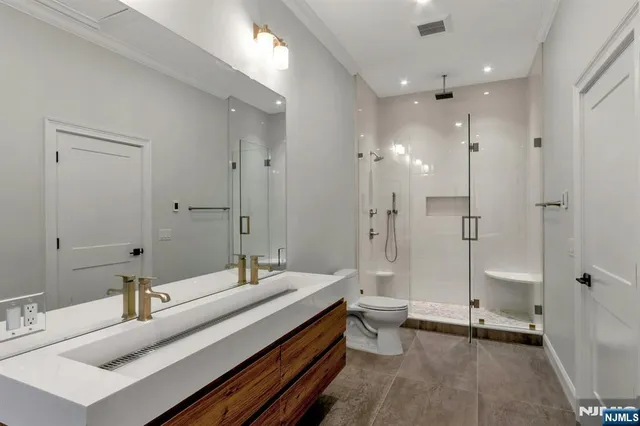 a bathroom with a double vanity sink toilet mirror and windows