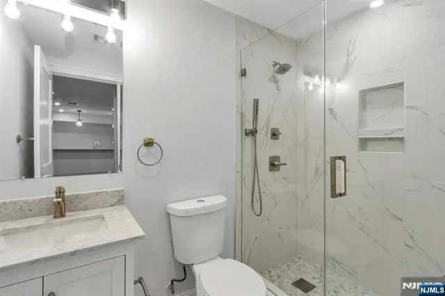 a bathroom with a granite countertop sink toilet a mirror and shower