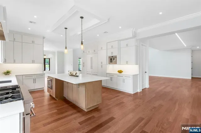 a large white kitchen with a stove a sink dishwasher and a refrigerator with wooden floor