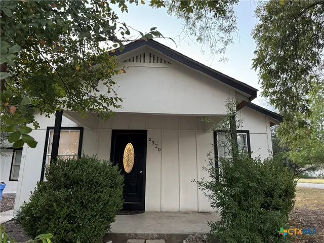 a front view of house with yard and trees in the background