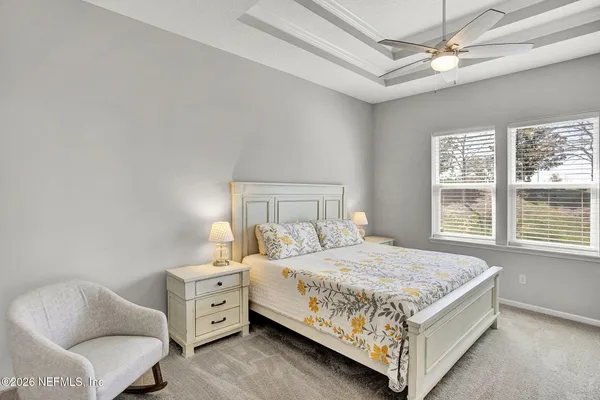 a bedroom with a bed a chair and two windows