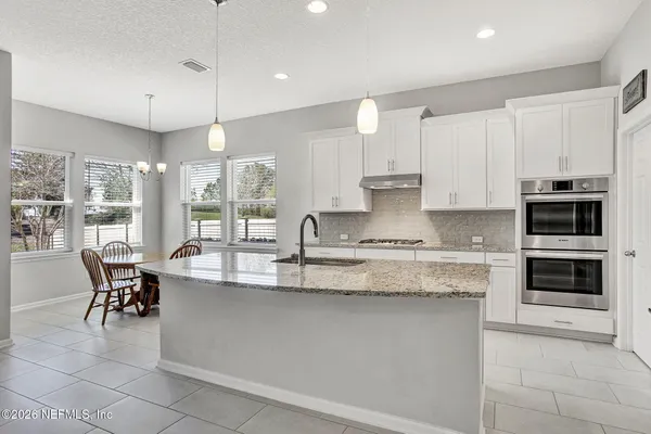 a large kitchen with granite countertop a stove a sink a dining table and chairs