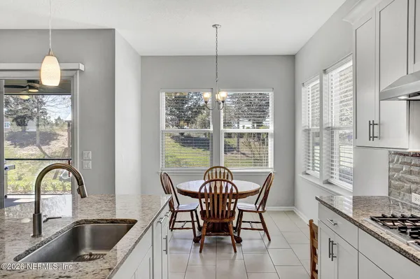 a kitchen with stainless steel appliances kitchen island granite countertop a refrigerator a stove a sink dishwasher with a dining table and chairs with wooden floor