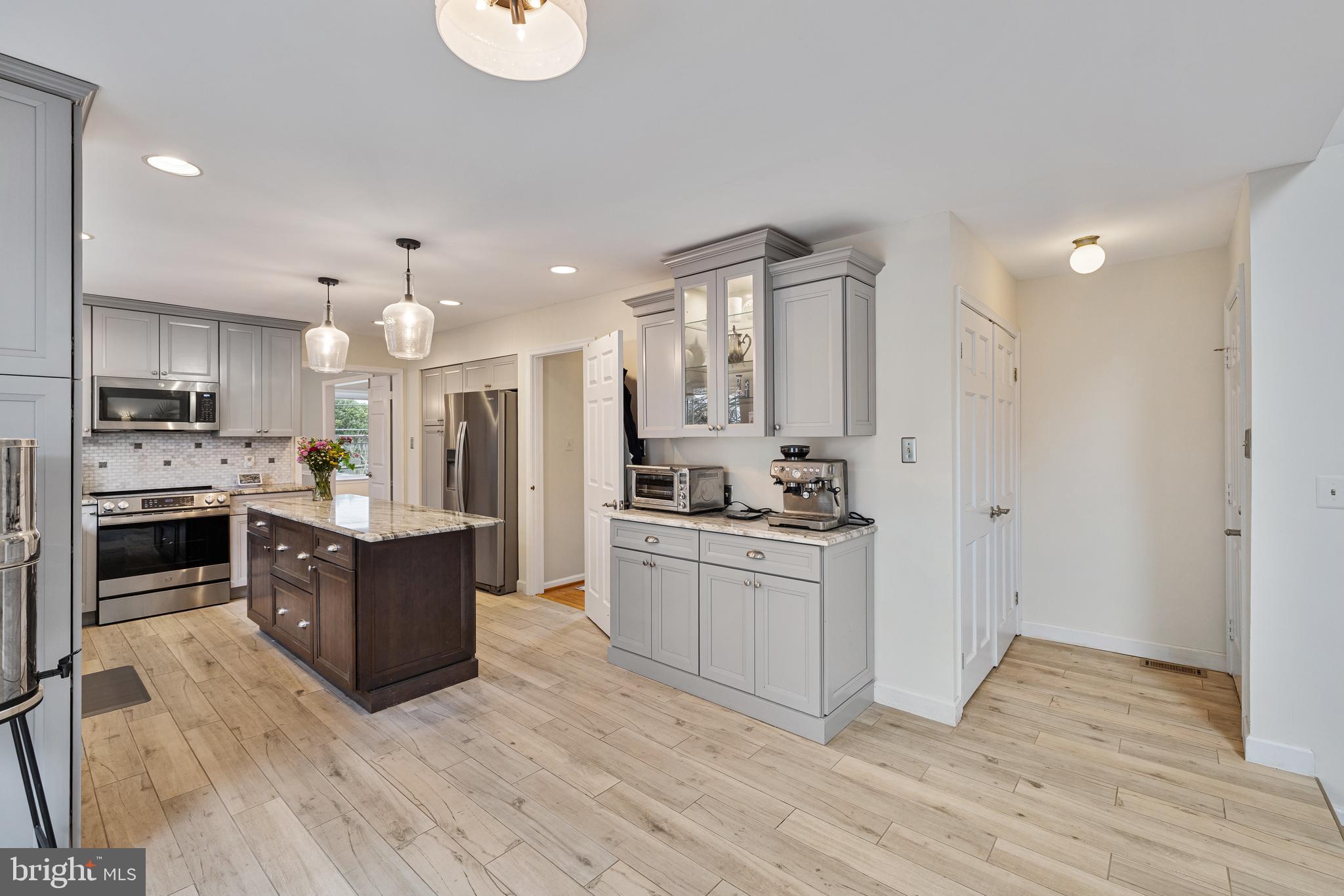 1439 Millikens Bend Road Herndon, VA 20170 - Photo 44 of 46 a large kitchen with stainless steel appliances kitchen island granite countertop a stove a sink a refrigerator and white cabinets with wooden floor