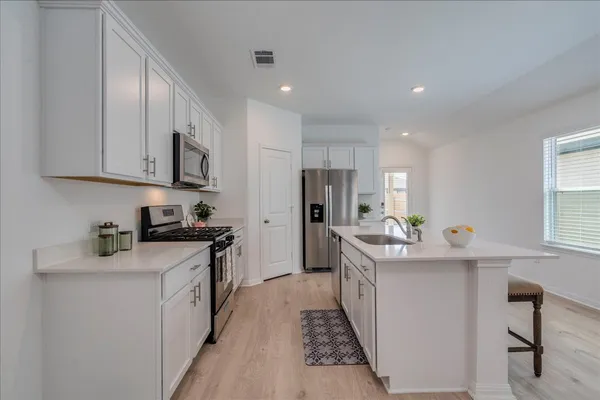 a kitchen with stainless steel appliances a sink stove top oven and cabinets