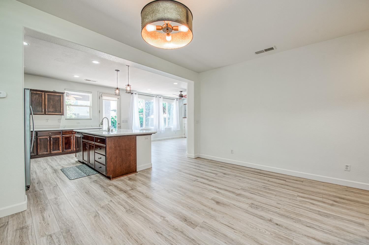 487 Everglade Avenue Clovis, CA 93619 - Photo 4 of 28 a kitchen with stainless steel appliances granite countertop a stove a sink a refrigerator white cabinets and wooden floor