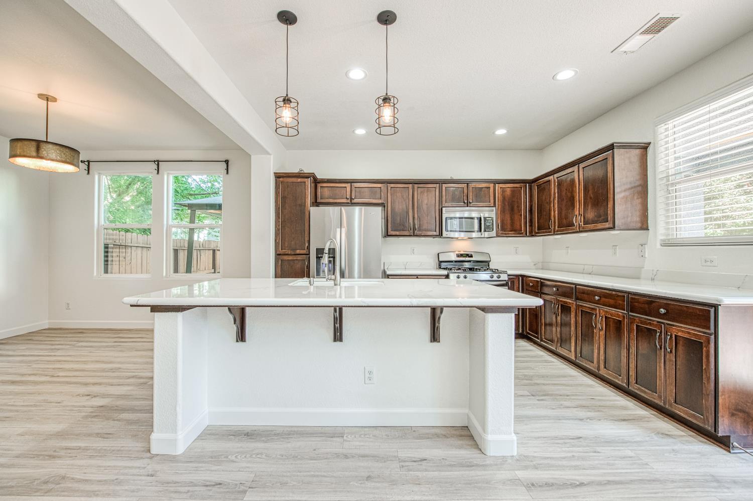 487 Everglade Avenue Clovis, CA 93619 - Photo 5 of 28 a large kitchen with kitchen island a large island in the center and stainless steel appliances