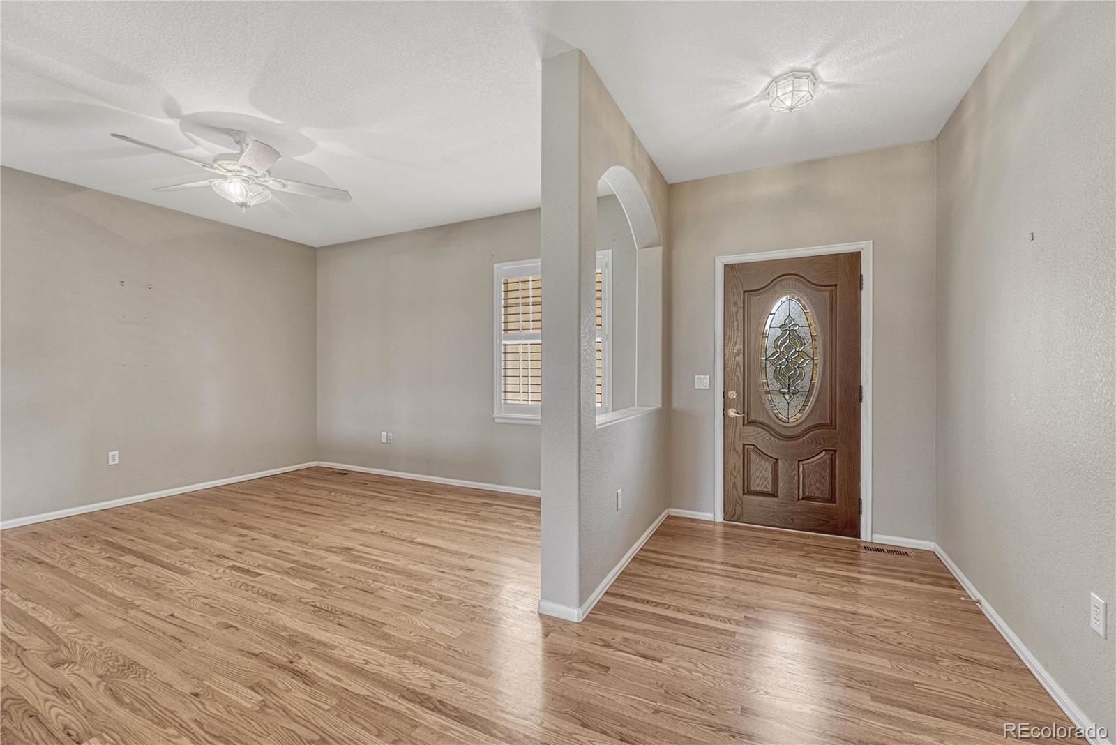 8107 South Catawba Court Aurora, CO 80016 - Photo 5 of 46 an empty room with wooden floor and entrance