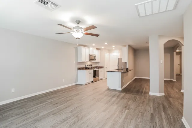 a view of kitchen with stainless steel appliances refrigerator stove and wooden floor