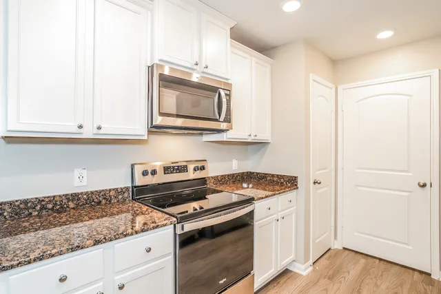 a kitchen with stainless steel appliances granite countertop white cabinets and a stove a oven with white countertops