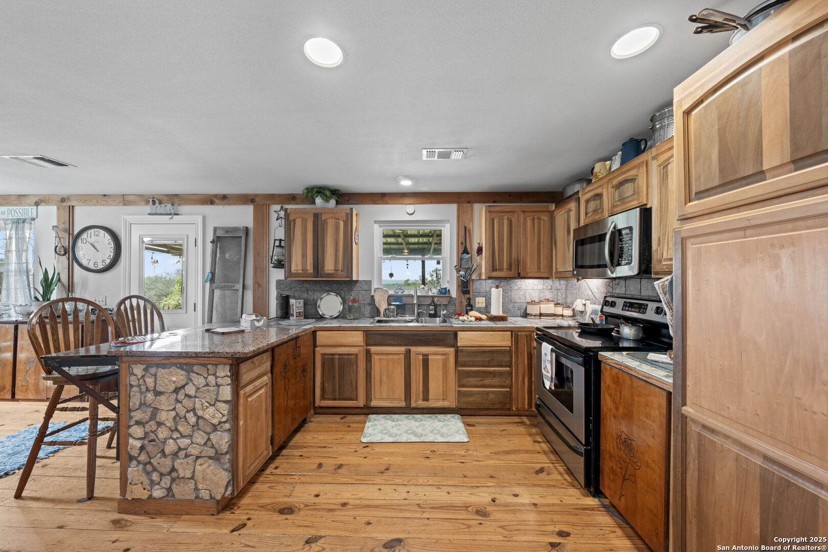 943 Stoneleigh Road Center Point, TX 78010 - Photo 14 of 36 a large kitchen with stainless steel appliances granite countertop a stove top oven a sink dishwasher and cabinets with wooden floor