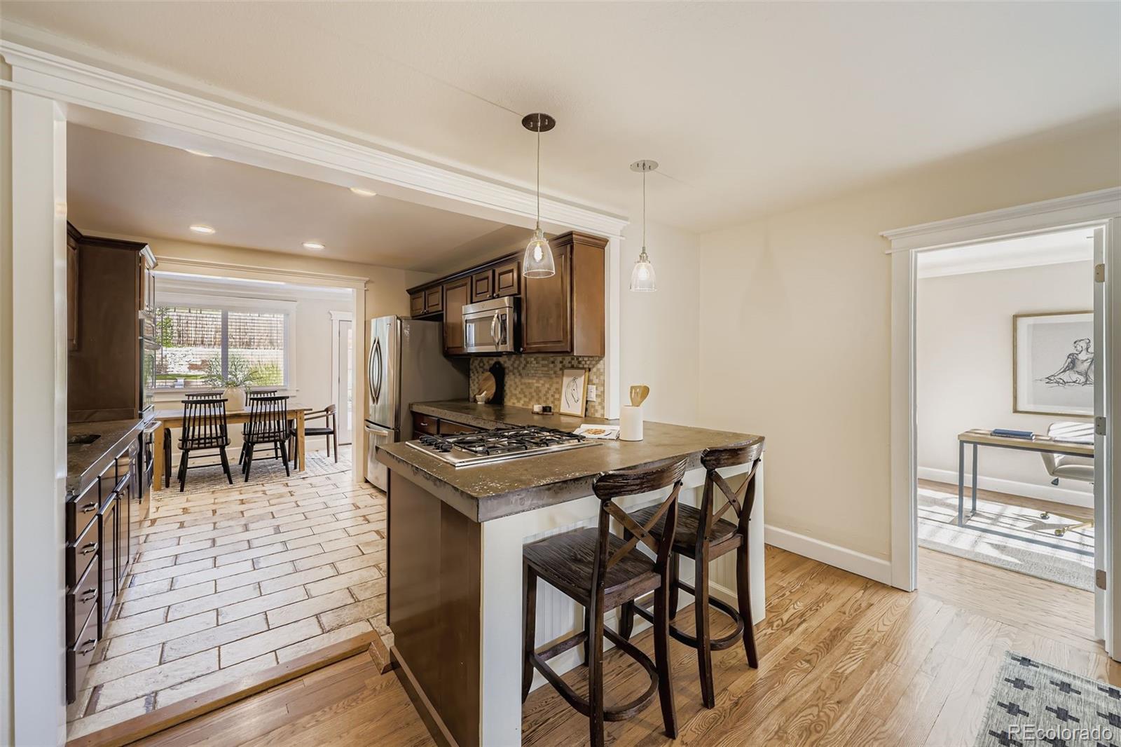 120 Gilbert Street Castle Rock, CO 80104 - Photo 9 of 25 a kitchen with stainless steel appliances granite countertop a stove top oven a sink a dining table and chairs with wooden floor