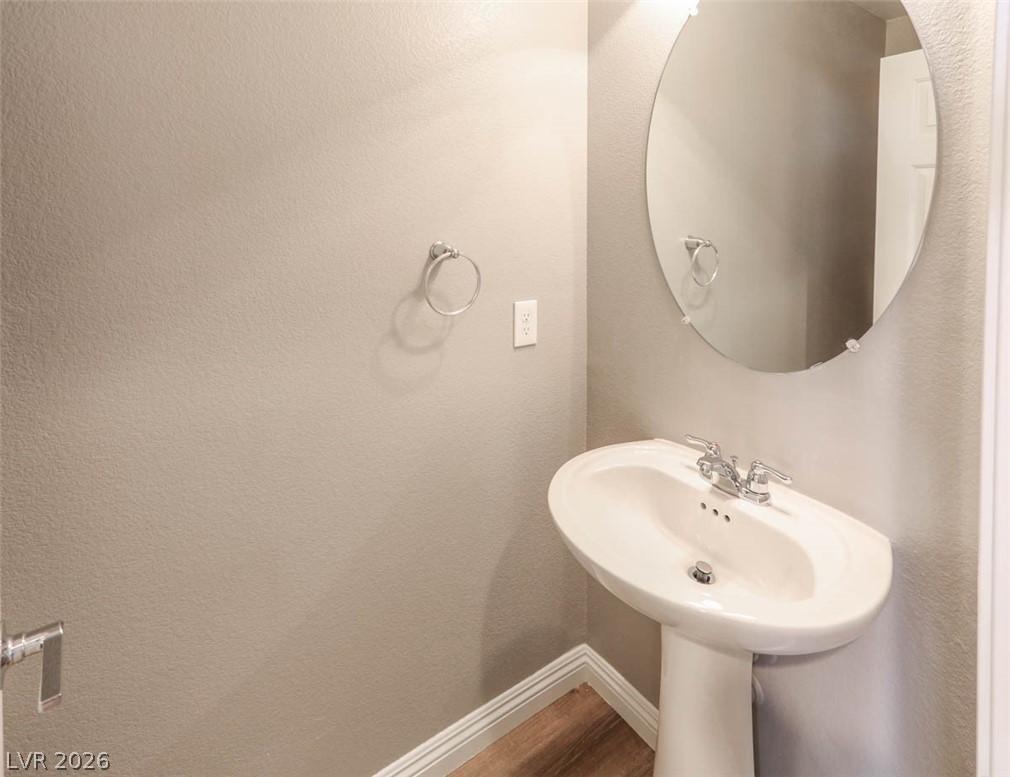 9940 Sable Point Street Las Vegas, NV 89178 - Photo 23 of 40 Bathroom featuring baseboards, wood finished floors, and a sink