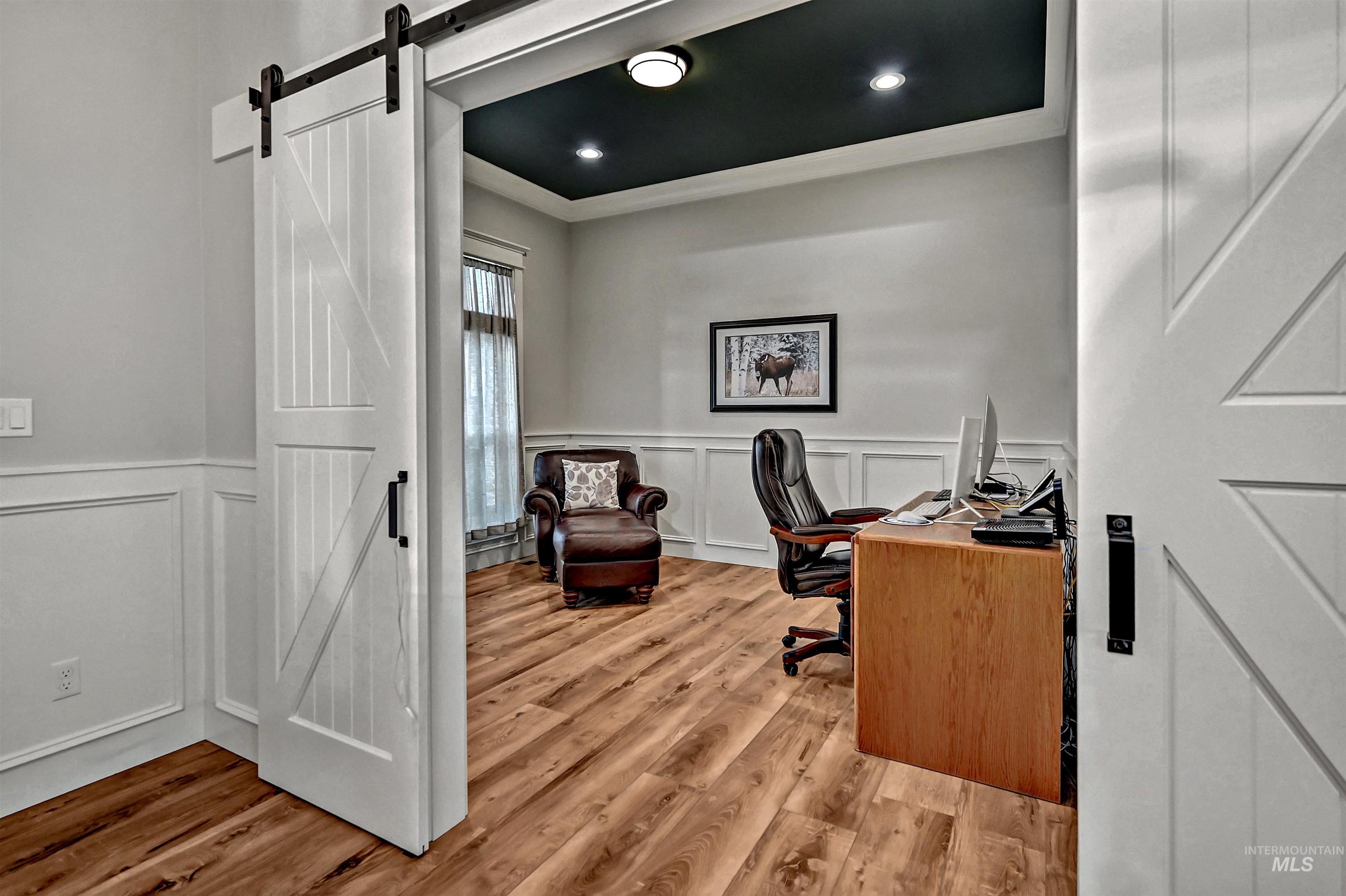 14964 Mortensen Court Caldwell, ID 83607 - Photo 18 of 38 Home office featuring a barn door, a decorative wall, a wainscoted wall, light wood-style flooring, and crown molding