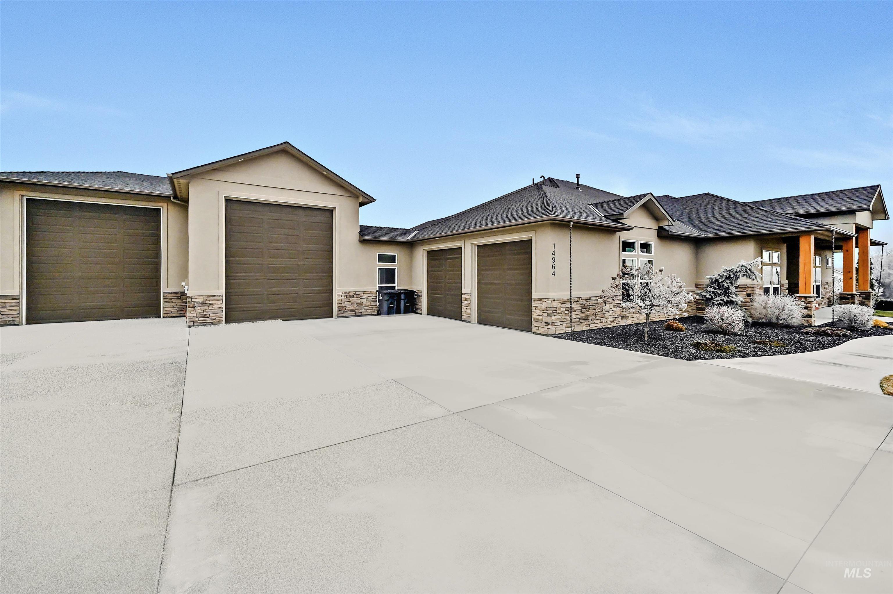 14964 Mortensen Court Caldwell, ID 83607 - Photo 2 of 38 Prairie-style home featuring stone siding, a garage, stucco siding, driveway, and roof with shingles