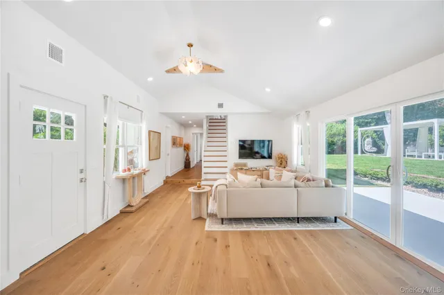 a kitchen with stainless steel appliances a stove a sink a oven a dining table and chairs with wooden floor