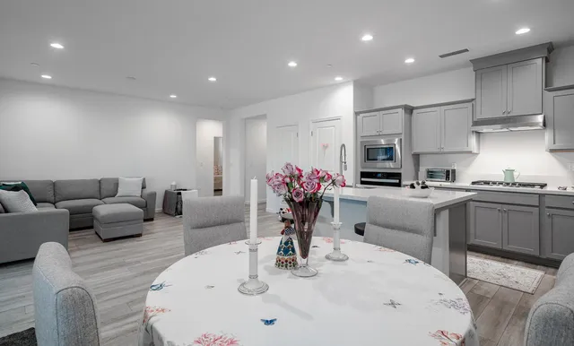 a kitchen with stainless steel appliances kitchen island granite countertop a sink a refrigerator and white cabinets