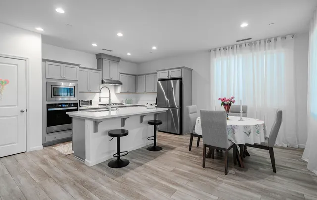 a kitchen with granite countertop white cabinets stainless steel appliances and dining table