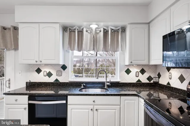 a kitchen with granite countertop a stove a sink and dishwasher wooden cabinets with granite countertops