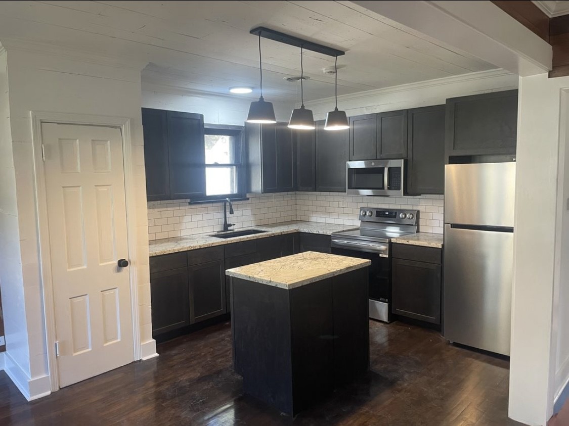 321 South Arcola Street Angleton, TX 77515 - Photo 3 of 7 a kitchen with stainless steel appliances granite countertop a refrigerator a sink dishwasher a stove and a microwave oven on the wooden floor