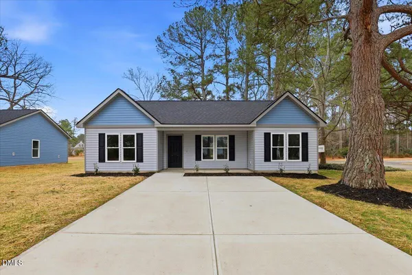 a front view of house with yard and trees in the background